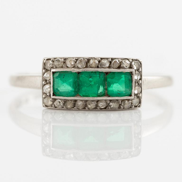 Ring in platinum set with step-cut emeralds and rose-cut diamonds.
