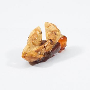 A carved amber figure/pendant of two squirrels sitting on some fruit, early 20th Century.