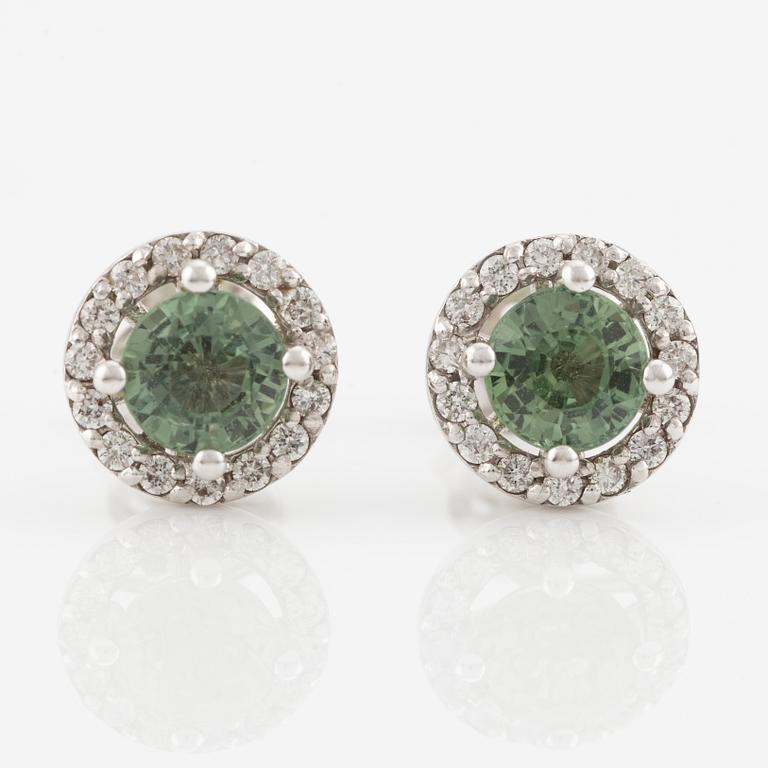 A pair of 18K gold earrings with green faceted sapphires and round brilliant-cut diamonds.