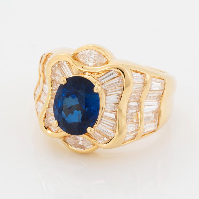 An 18K gold Junod ring set with a facted sapphire and tapered baguette-cut diamonds.