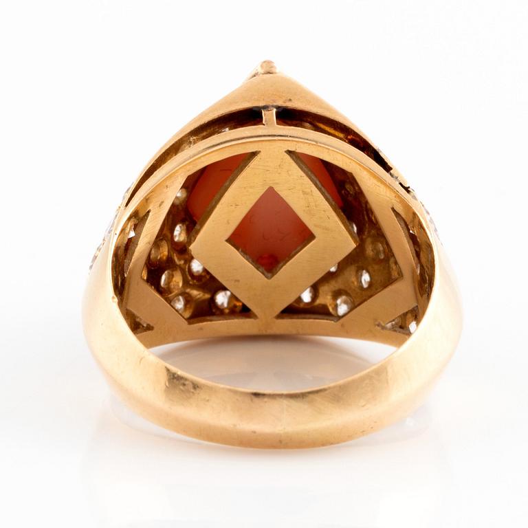 An 18K gold and coral ring set with round brilliant-cut diamonds.
