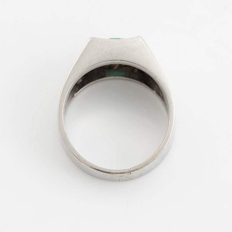 An 18K white gold ring set with a step-cut emerald and round brilliant-cut diamonds.