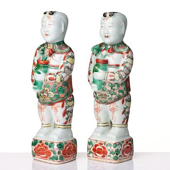 A pair of wucai decorated porcelain figurines of boys with flowers, Qing dynasty, Kangxi (1662-1722).