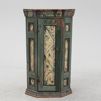 A painted corner cabinet, dated 1810.