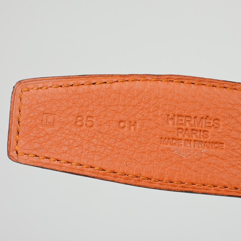 HERMÈS, a reversible belt, togo orange and black leather with silver colored H belt buckle.