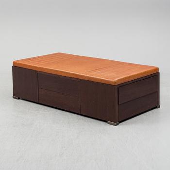 A contemporary bench with drawers and leather upholstery.