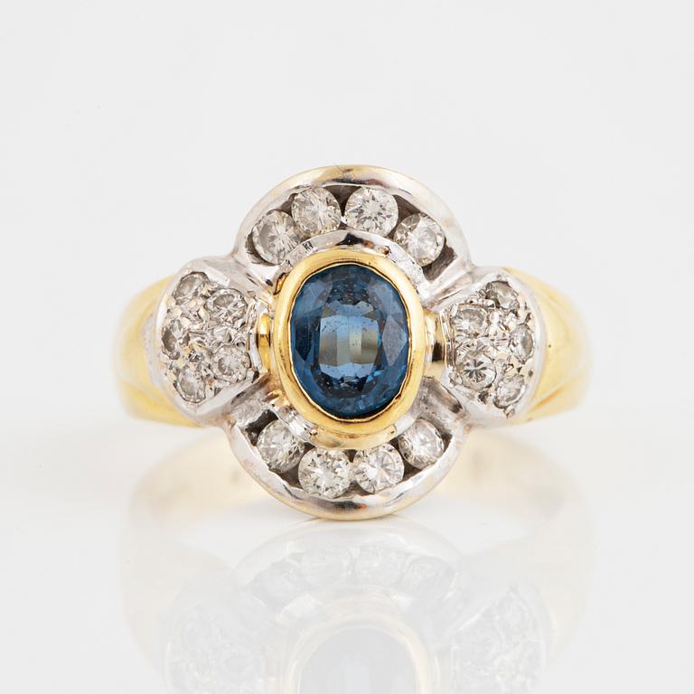 An 18K gold ring set with a synthetic sapphire and round brilliant-cut diamonds.