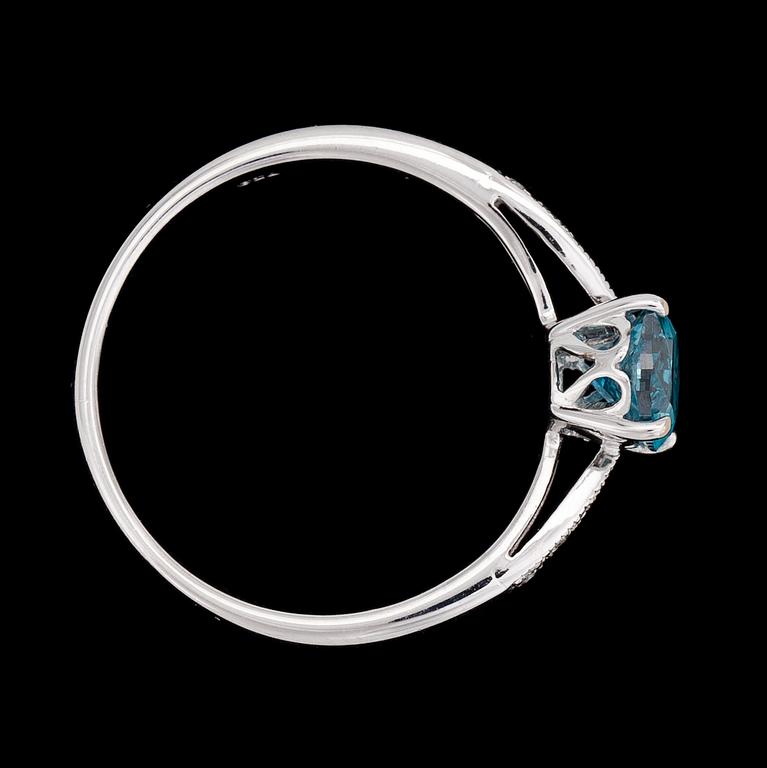 RING, behandlad ovalt briljantslipad blå diamant, ca 1 ct,  med små vita briljantslipade diamanter på sidorna.