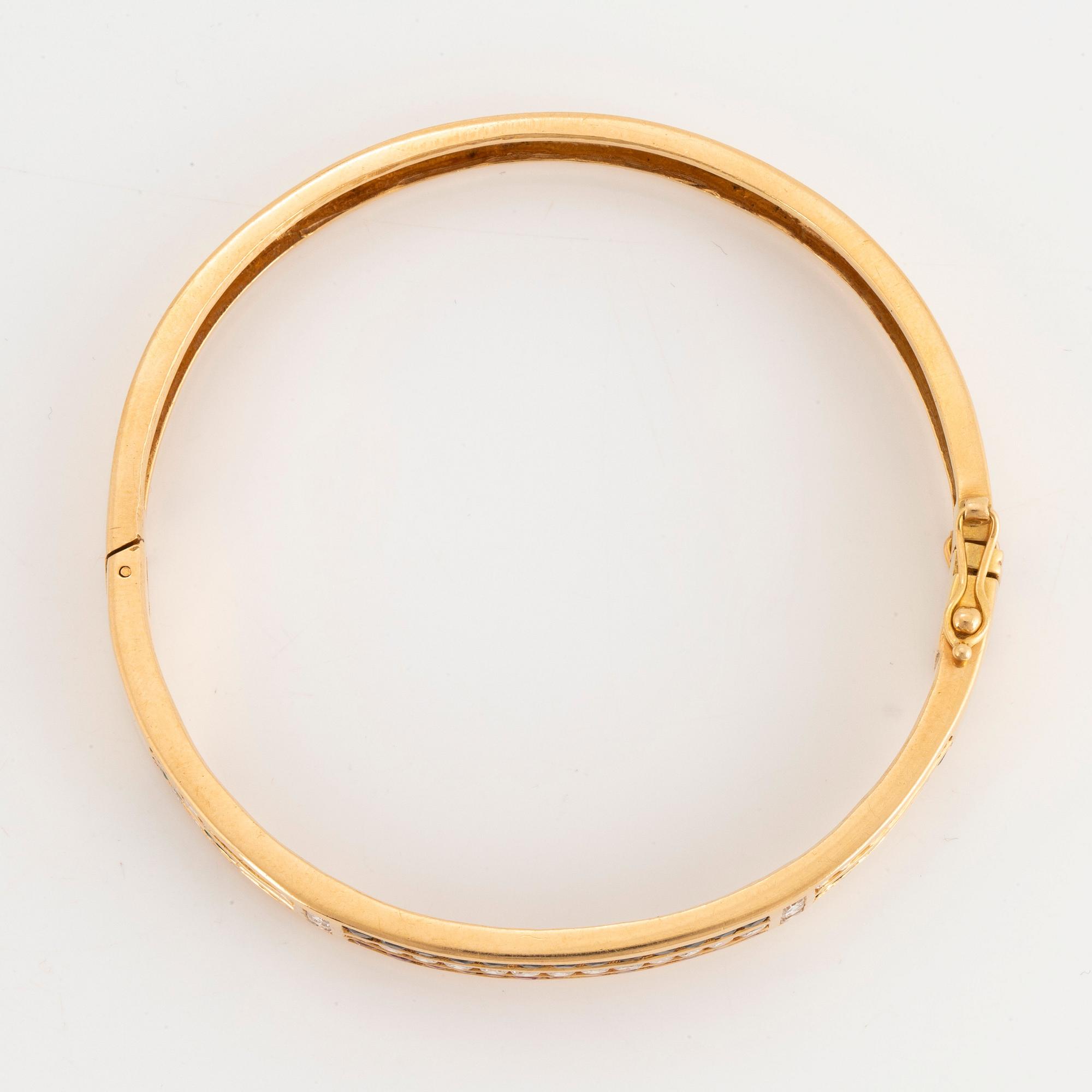 An 18K gold bangle set with round brilliant-cut diamonds, sapphires, emeralds and rubies.