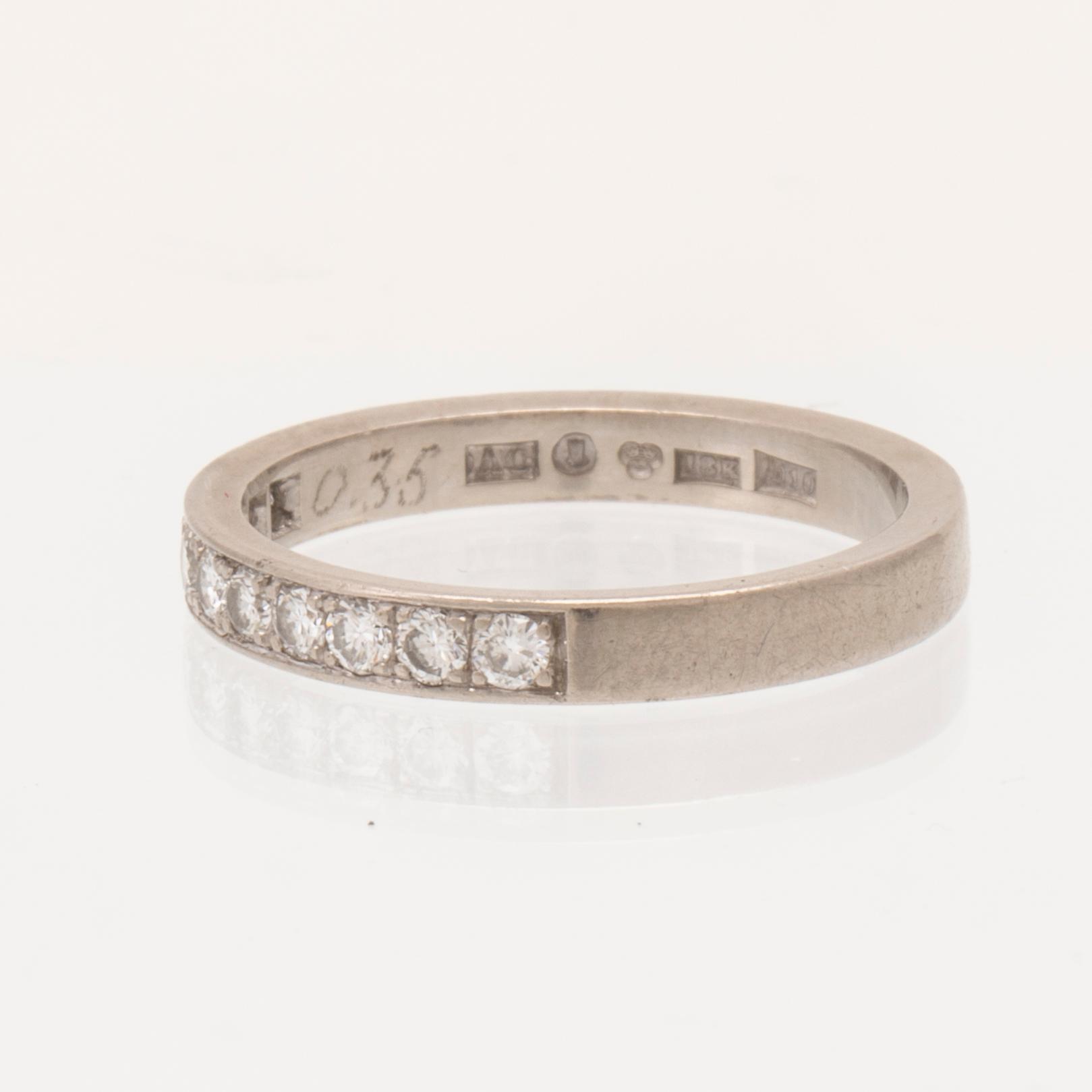 An 18K white gold half eternity ring set with round brilliant-cut diamonds.