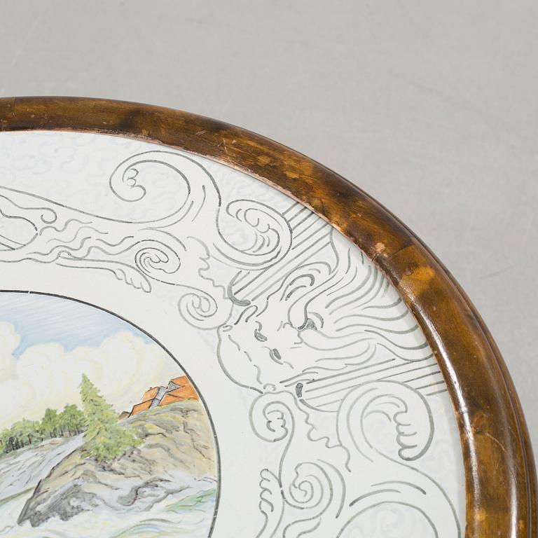 A table from the first halft of the 20th century with a "Kalmar Fajans" tabletop, painted by John Sjöstrand.