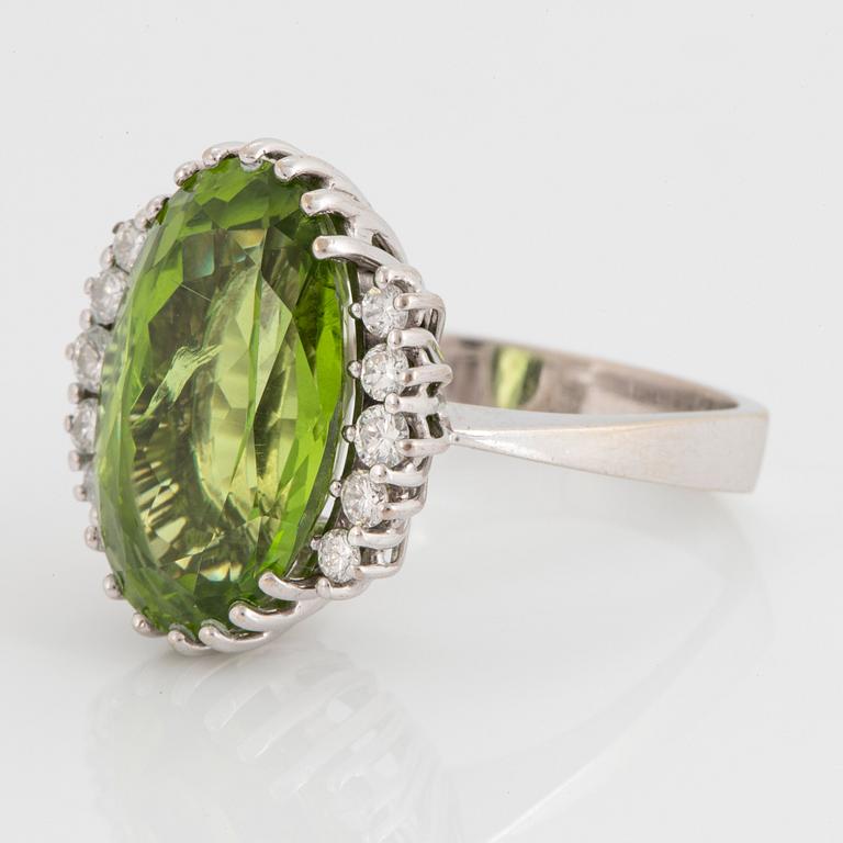 An 18K white gold ring set with an oval faceted peridot ca 11.00 cts and round brilliant-cut diamonds.