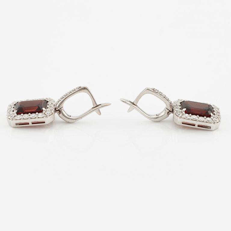 A pair of earrings in 18K white gold with faceted garnets and round brilliant-cut diamonds.