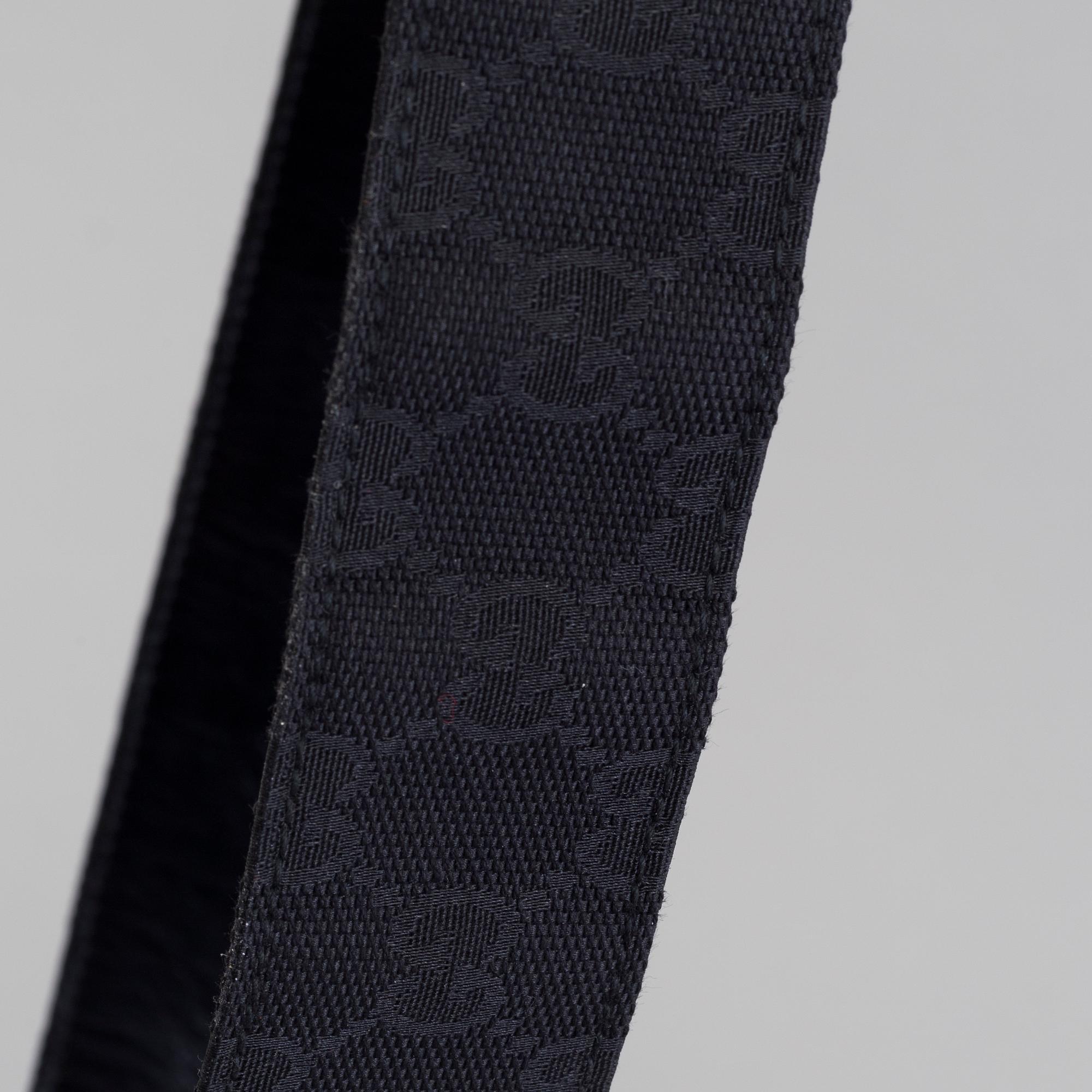 A blach monogram belt by Gucci.