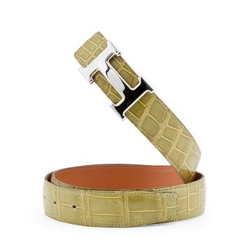 HERMÈS, a green crocodile belt with silver colored H belt buckle.