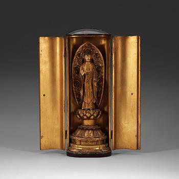 A Japanese gilt wooden figure of standing Buddha in a lacquer shrine, Meiji (1868-1912).