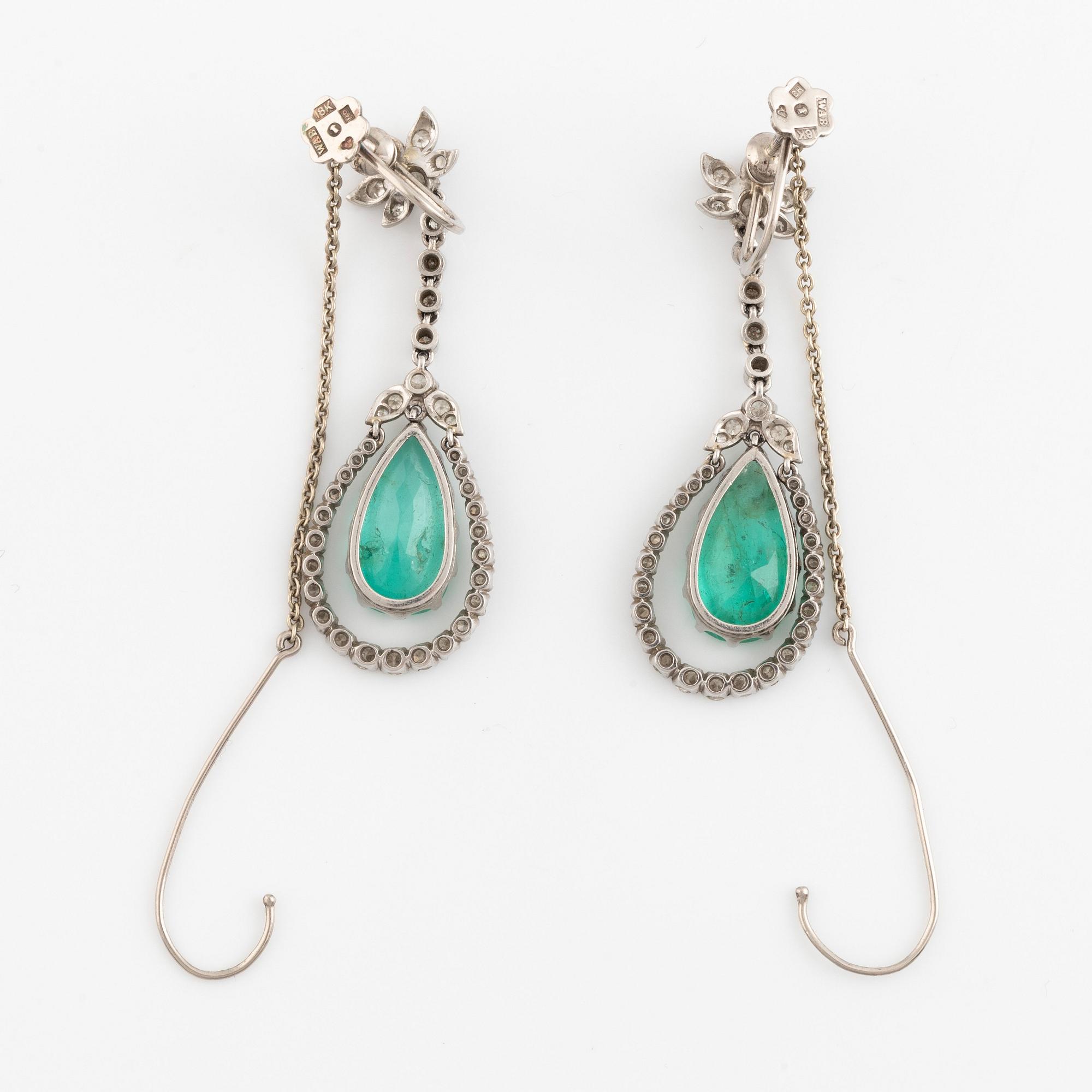 Ett par örhängen, med droppformade smaragder och diamanter.