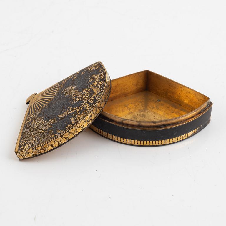 A Japanese gilt-bronze fan-shaped box and gilt iron tsuba with mei inscription, Meiji period (1868-1912).