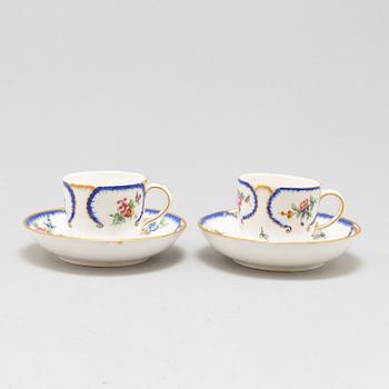 A pair of enamelled cups with dishes, France, Sèvres, 1780s.
