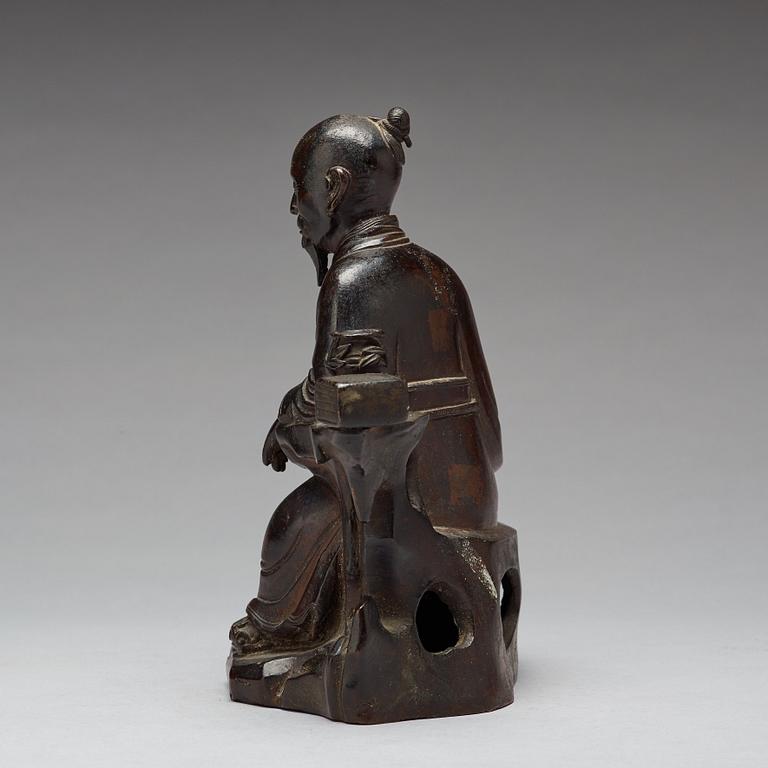 A bronze sculpture of a seated scholar with books, Qing dynasty (1644-1912).