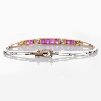 An 18K gold and platinum bracelet set with step-cut rubies and old- and rose-cut diamonds.