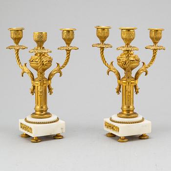 A late 19th century pendulum clock and a pair of candelabras.