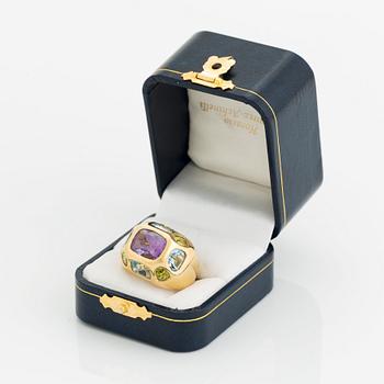 An 18K gold ring set with faceted amethyst, peridot and aquamarine.