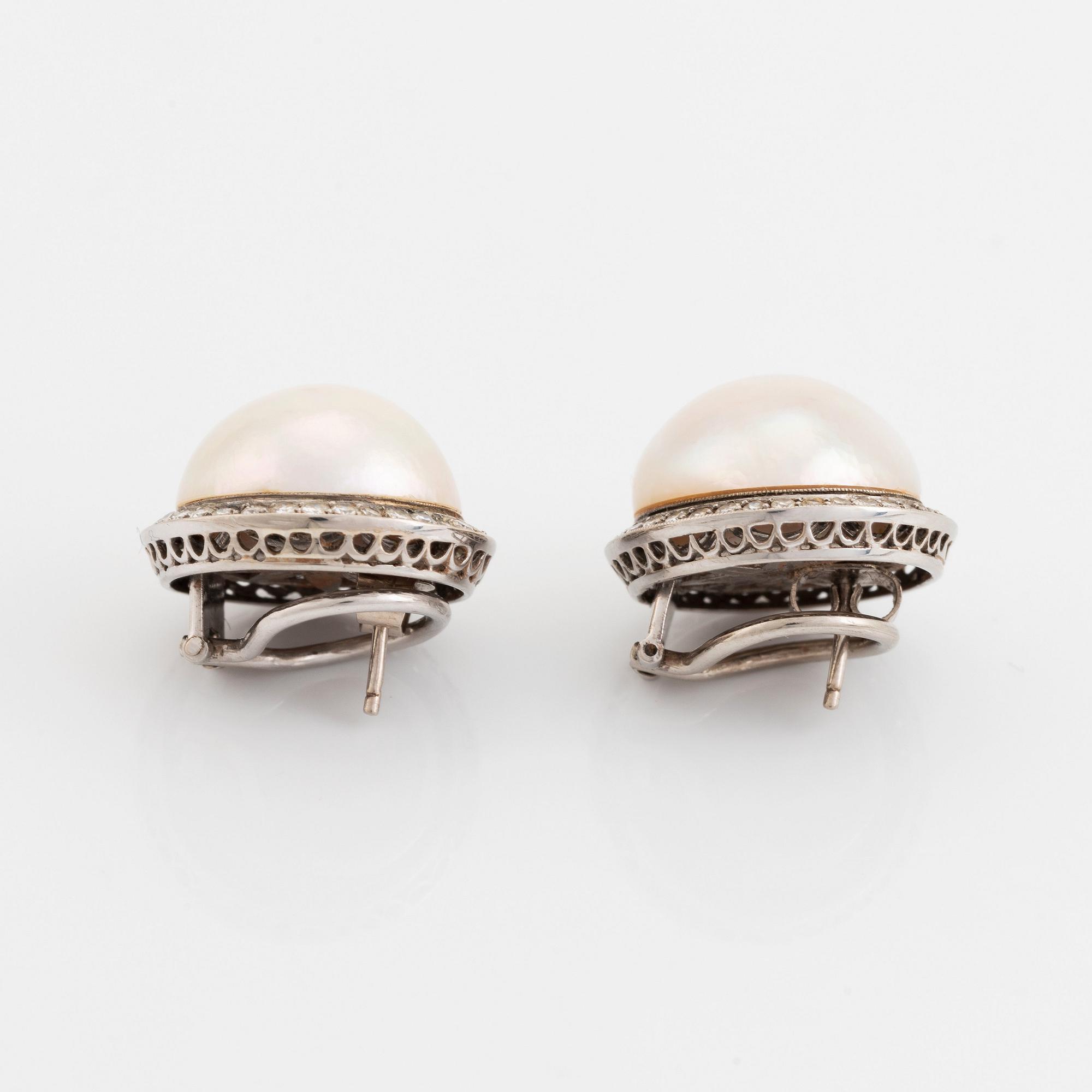 A pair of 18K white gold earrings set with cultured mabe pearls and round brilliant-cut diamonds.