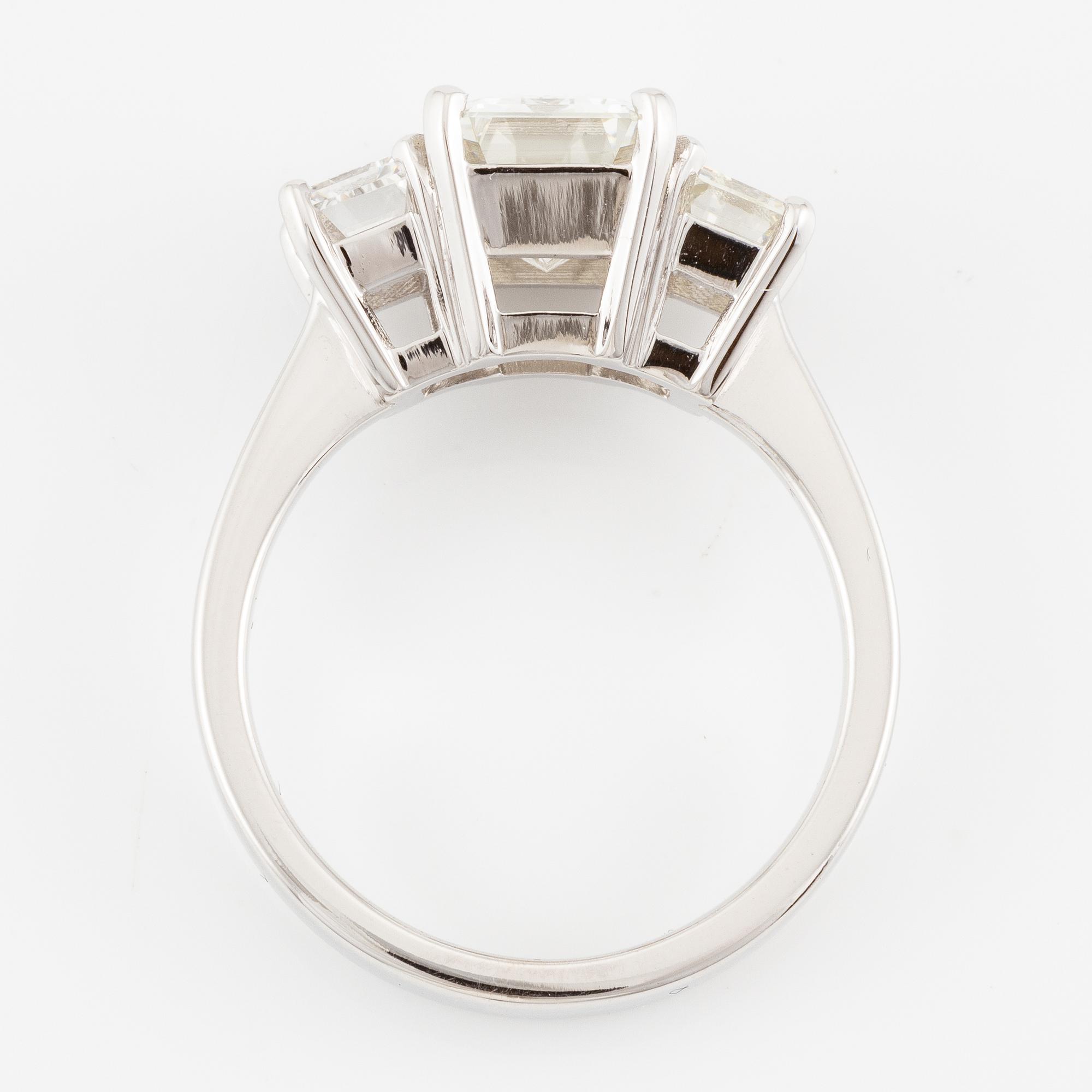 An 18K white gold ring set with three emerald-cut diamonds.