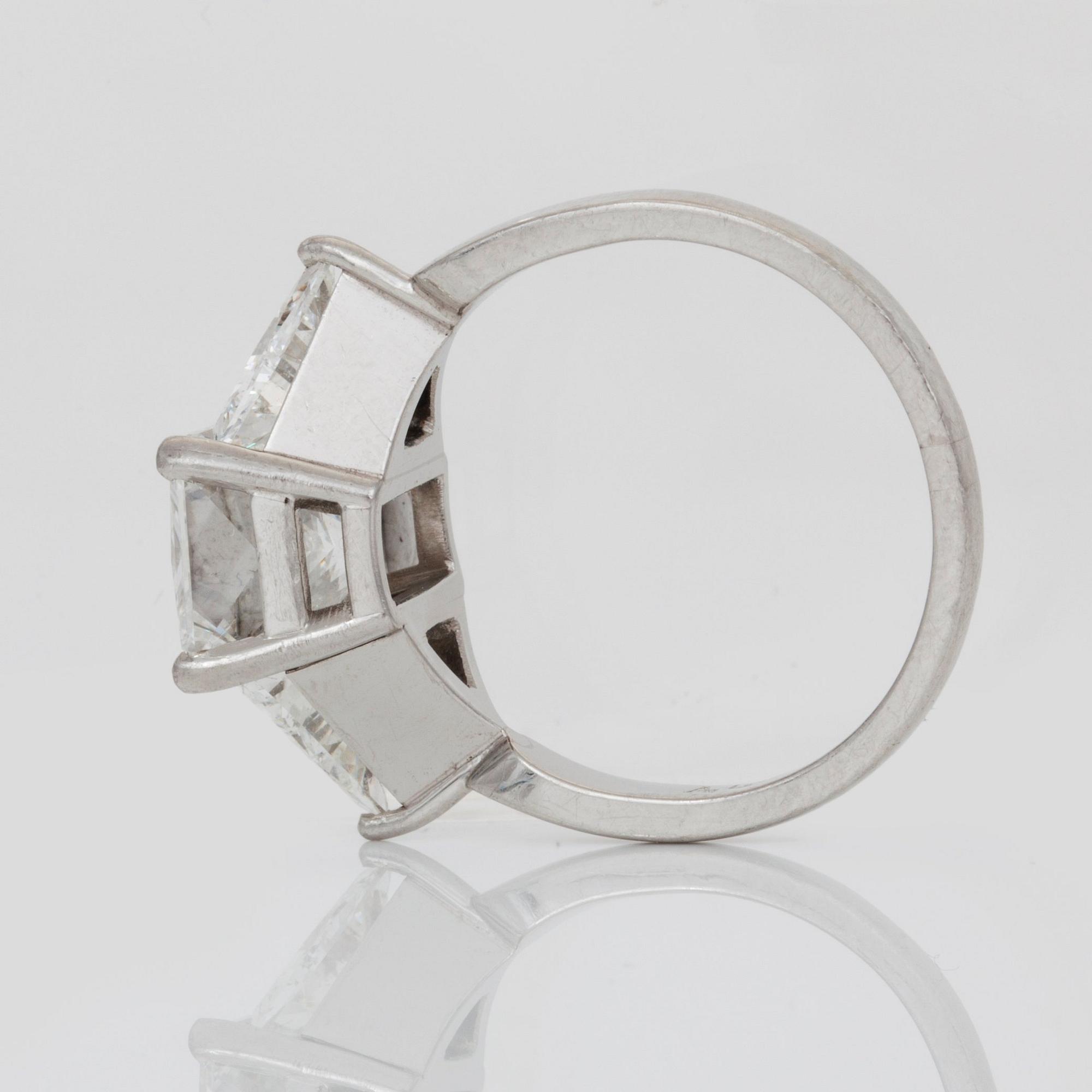 A radiant-cut diamond, 3.01 cts ring. Flanked by two triangular cut-diamonds, 0.50 ct each. E/VS2, certificate from HRD.