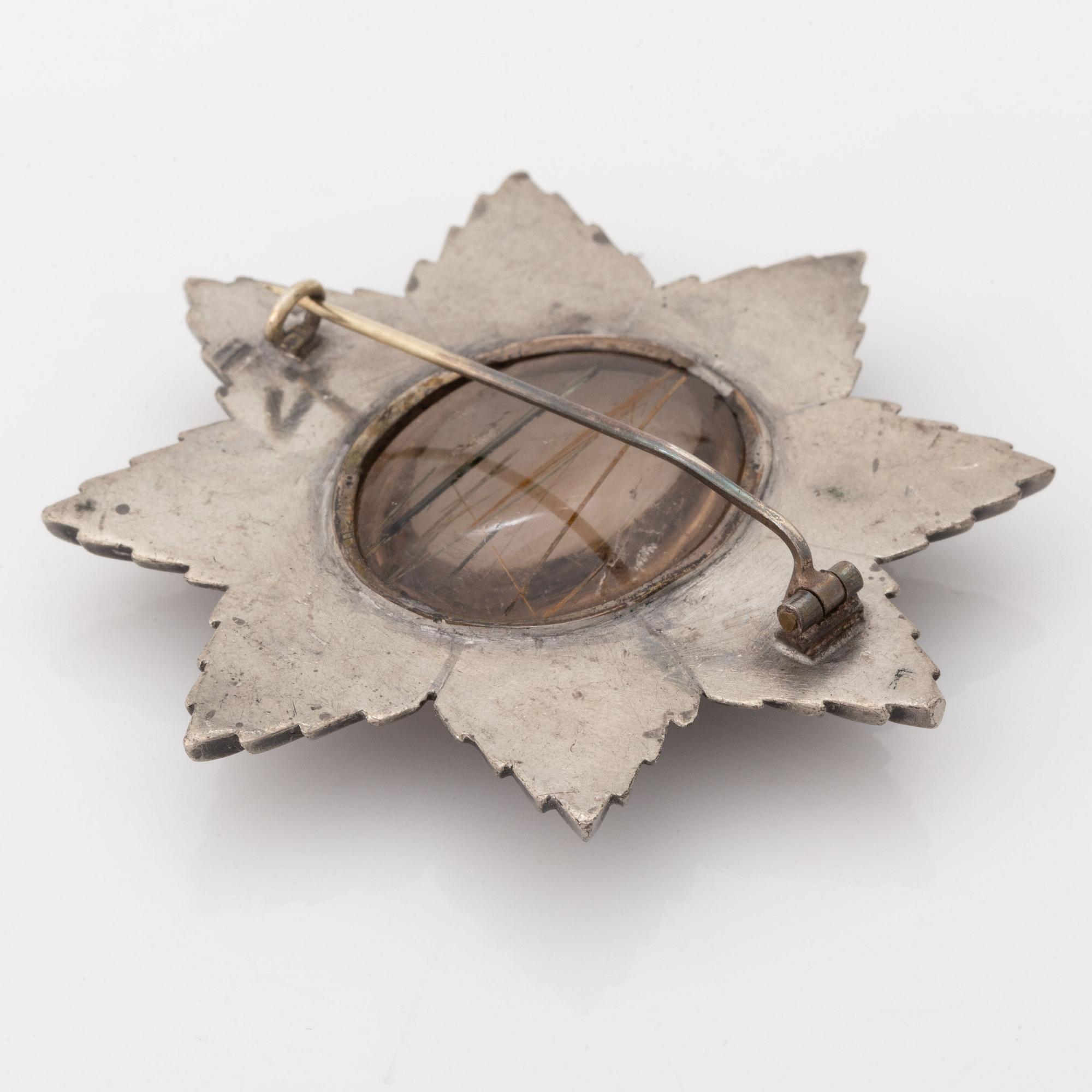 A brooch in grey metal set with rutile quartz.