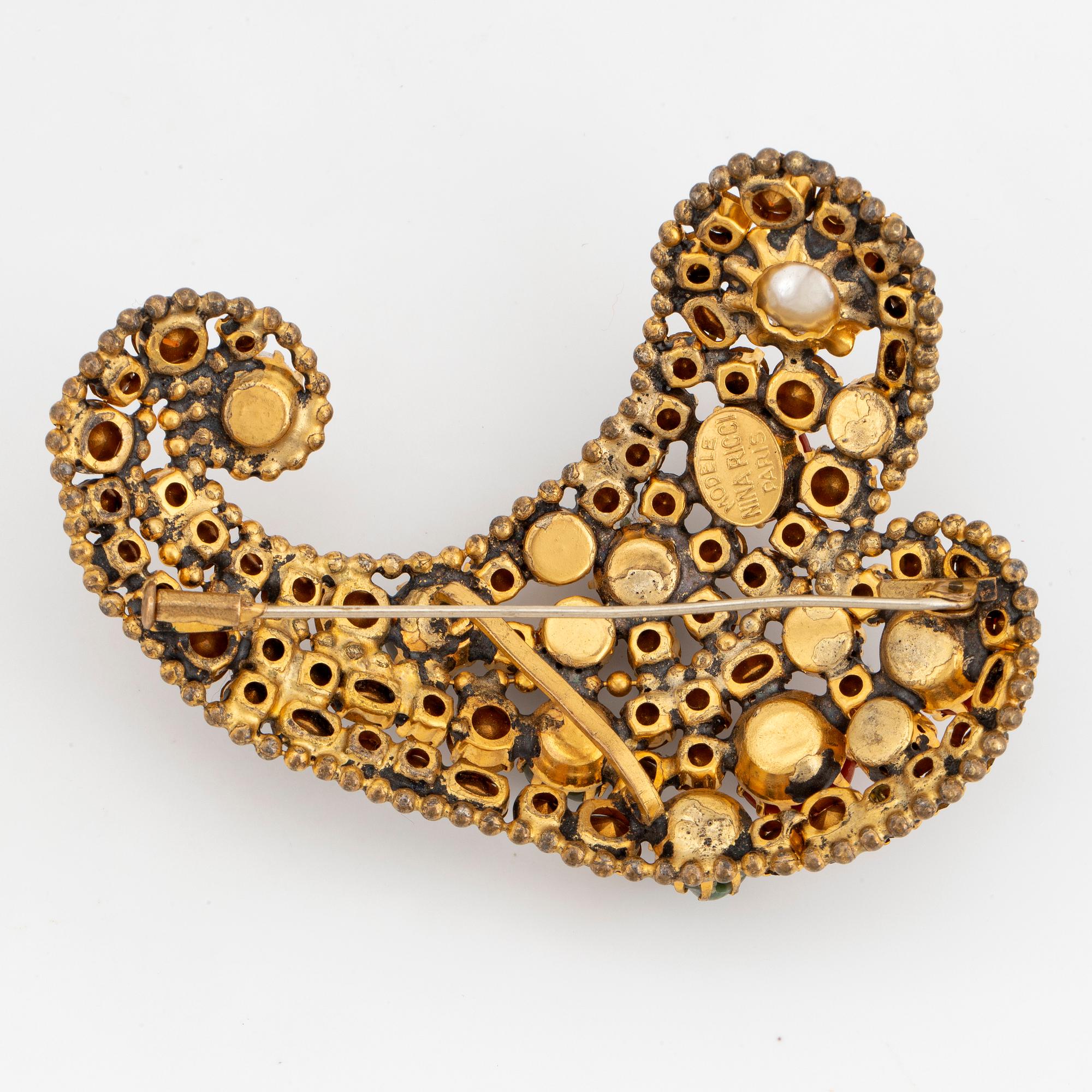 A Nina Ricci Brooch yellow metal set with stones and imitation pearls. Bukowskis