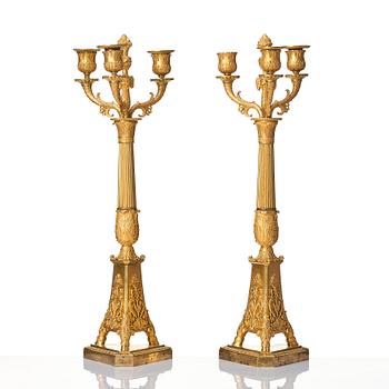 A pair of French Empire three-branch ormolu candelabra, early 19th century.