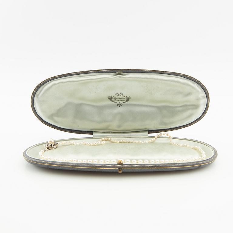 Necklace of cultured pearls and a clasp of 18K white gold set with round brilliant-cut diamonds and a cultured pearl.