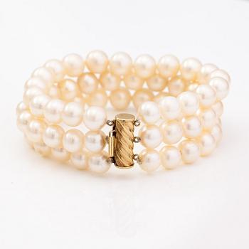 A three-strand pearl bracelet with cultured pearls and a 14K gold clasp.