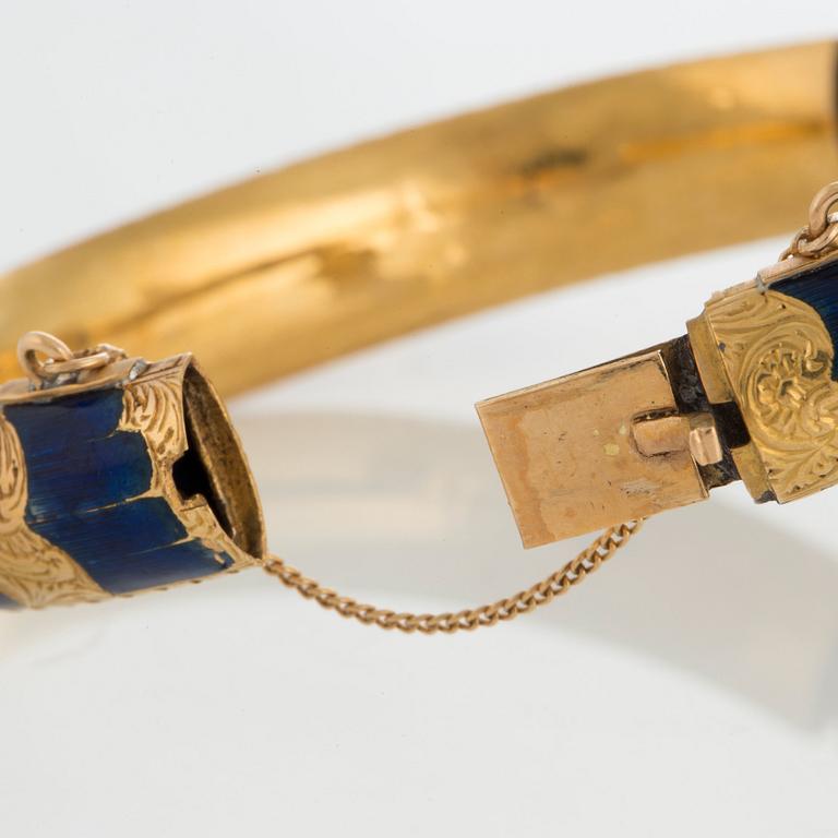 An 18K gold snake bangle decorated with blue enamel and set with an opal and a rose-cut diamond.