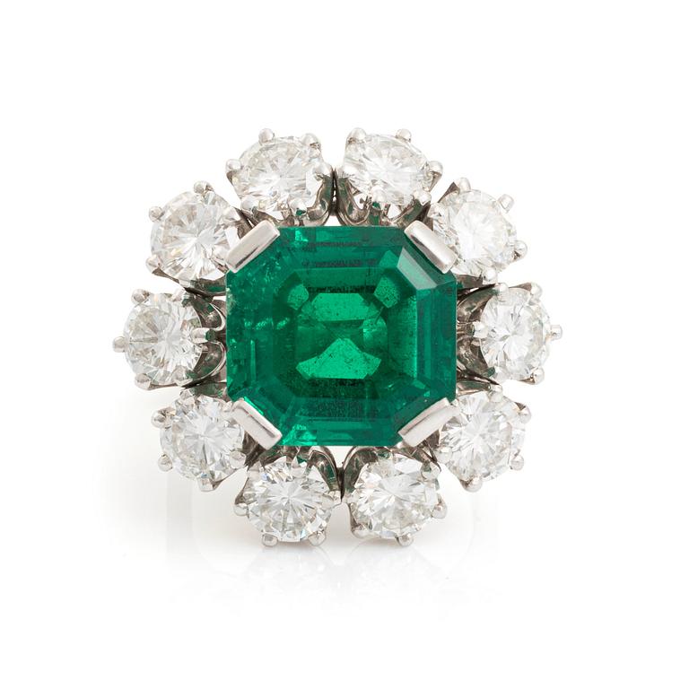 A WA Bolin platinum ring set with a step-cut emerald and round brilliant-cut diamonds.
