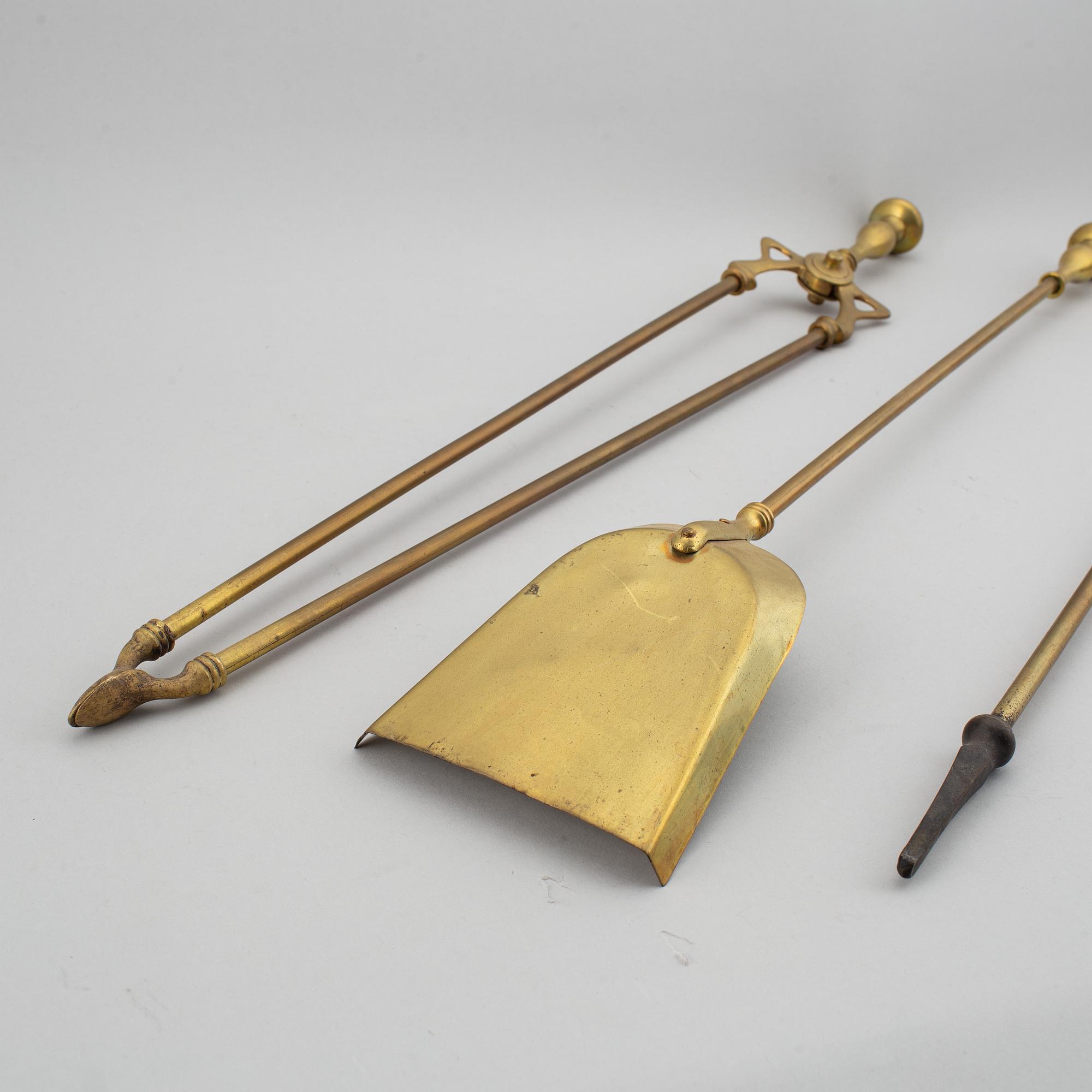 A pair of brass fire dogs and a brass fireplace poker set.