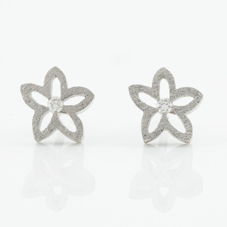 Ole Lynggard ett par örhängen i form av blommor.