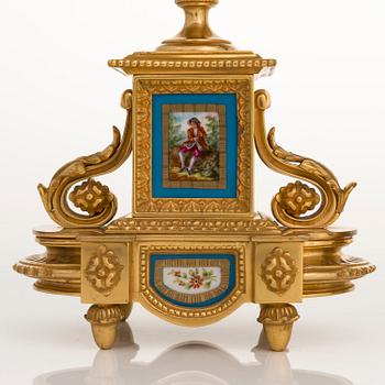 A mid-19th-century French gilt-brass mantel clock with a pair of candelabra by Dussault.