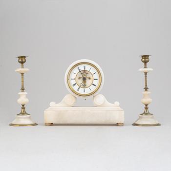 An alabaster mantle clock and pair of candlesticks, circa 1900.