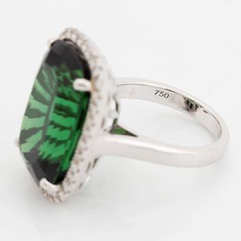 An 18K white gold ring set with a faceted green tourmaline and round brilliant-cut diamonds.