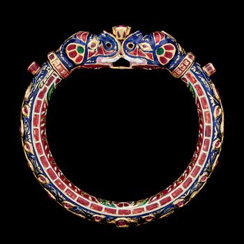 A cabochon cut ruby- and gold bangle with blue and red enamel, India, late 19th century.