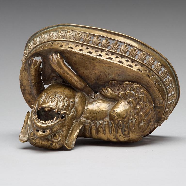 A copper alloy figure of a reclining buddhist lion, presumably 18th Century.