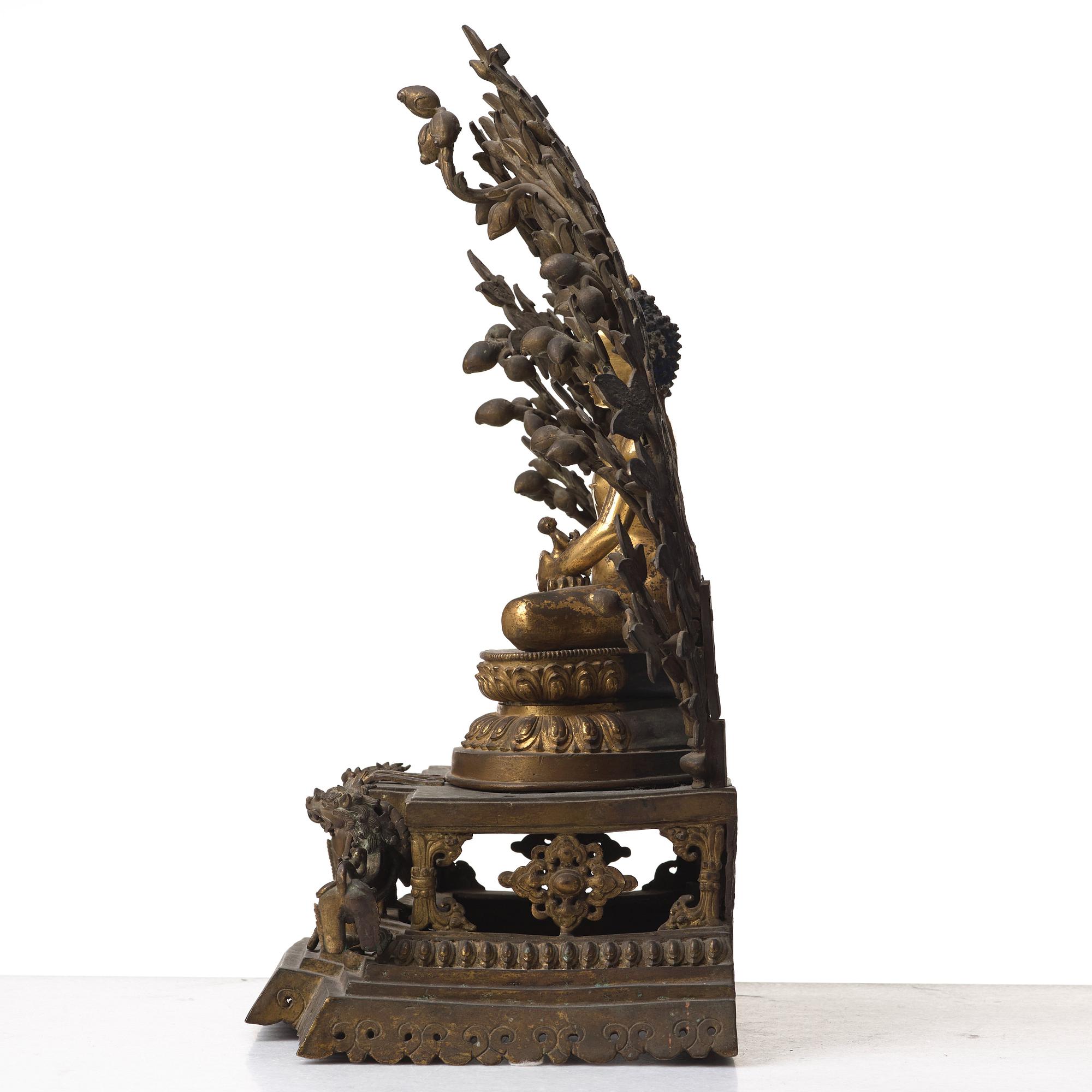 A large Nepalese gilt bronze buddha on a throne with mandorla, 18/19th Century.