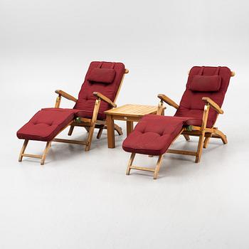 A pair of teak deck chairs and a table, 21st Century.