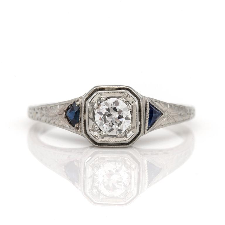 A ring with a round, old-cut diamond and probably faceted sapphires.