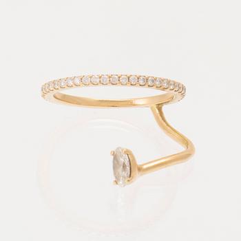 An 18K gold ring set with an oval cut and round brilliant cut diamonds by LWL Jewelry.