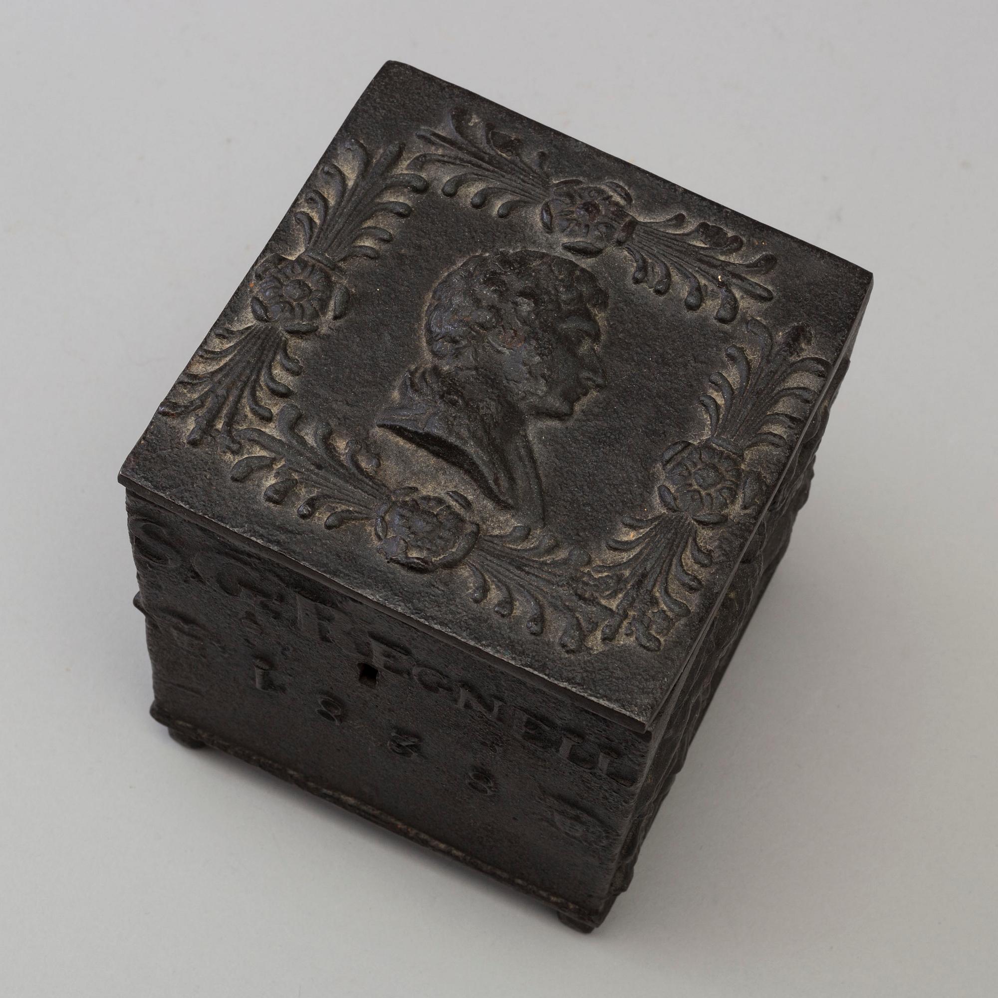 An empire cast iron tobacco box, dated 1838.