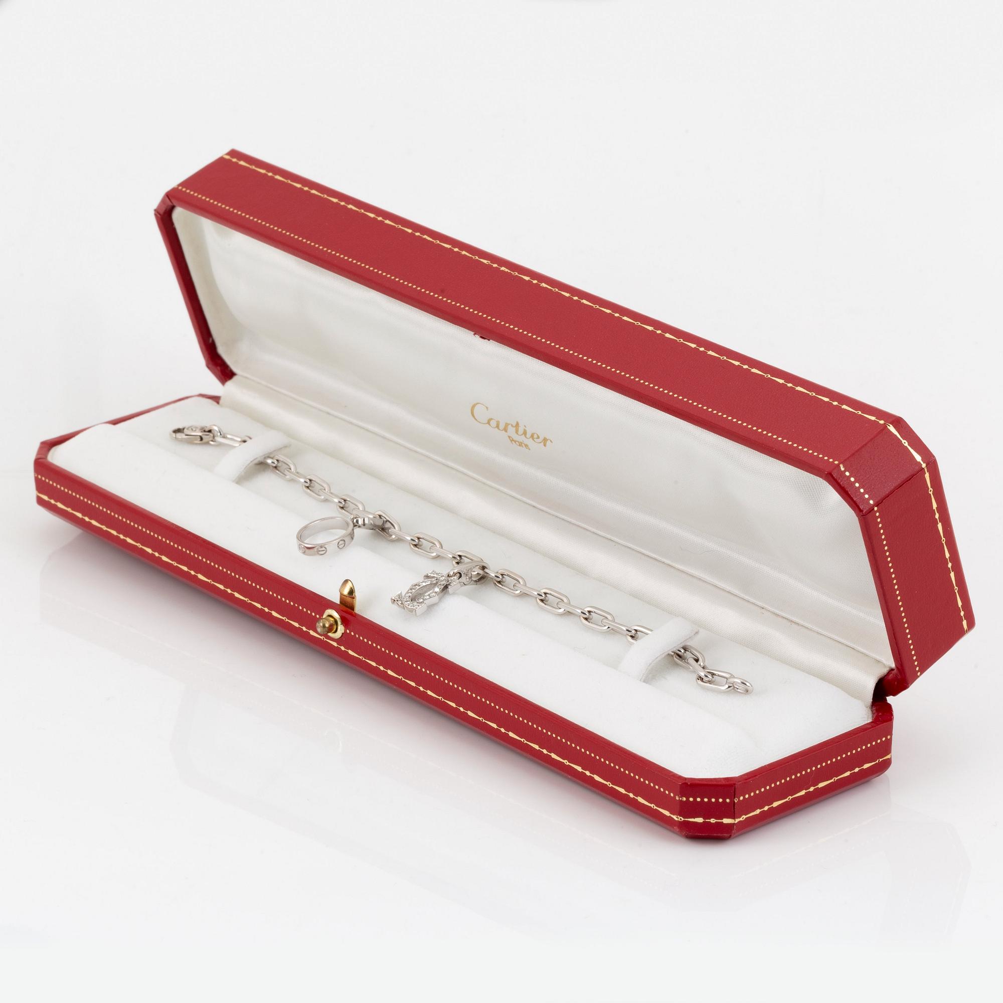 An 18K white gold Cartier "Spartacus" bracelet with two charms.